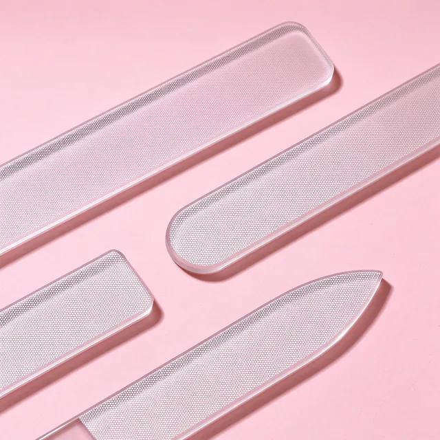 Four transparent glass nail files laid out so the etched abrasive faces catch the light