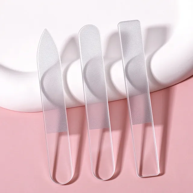Three clear glass nail files leaning inside a white dish