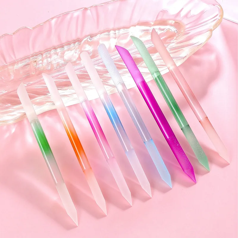 Ten translucent crystal-glass nail sticks in assorted colours fanned across a glass dish