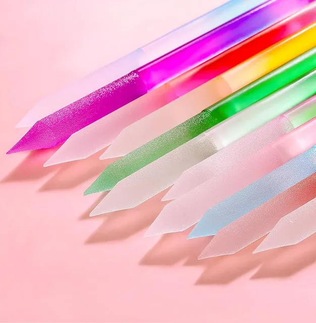 Crystal-glass nail sticks in magenta, green, blue and yellow laid across a pink cushion