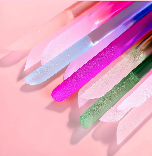 Colourful crystal-glass nail sticks crossing on a pink background
