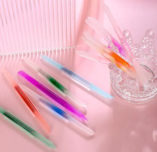 Crystal-glass nail sticks standing on a pink marble surface