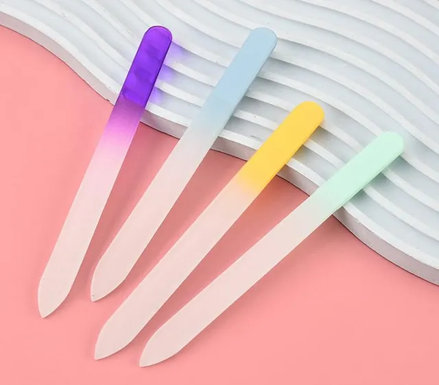 Four gradient glass nail files laid diagonally on a pink surface