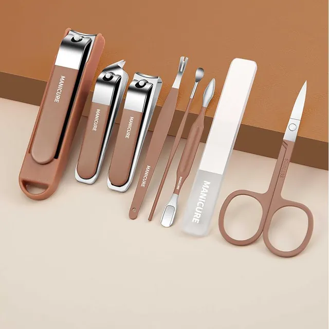 The kit's clippers, ear pick, cuticle tool, scissors and nail file laid in a row on a beige surface
