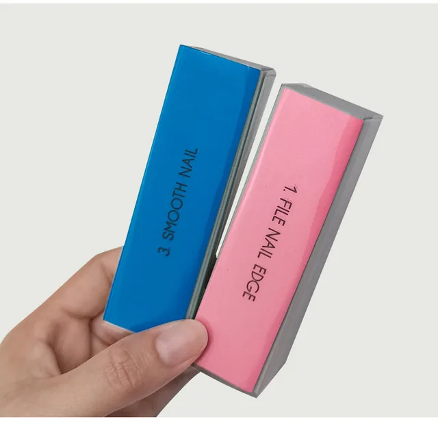 Hand holding a blue and a pink polishing block with the printed Buff Smooth Nail face toward the camera
