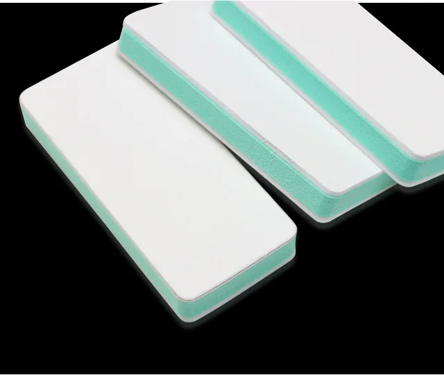 Two white buffing blocks with mint edges laid diagonally on a black background