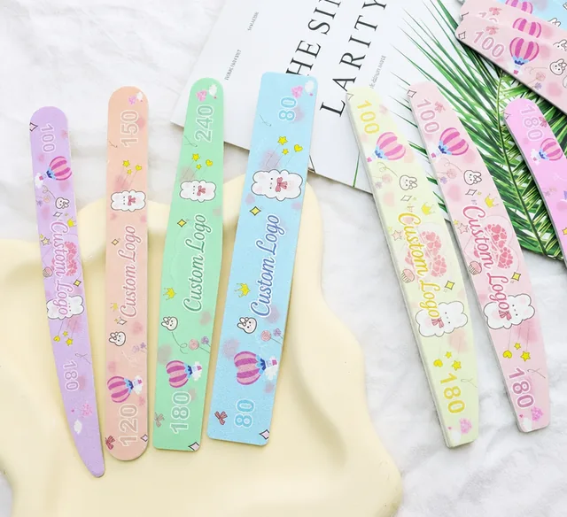 Eight pastel cartoon-print nail files arranged on a tray over a magazine