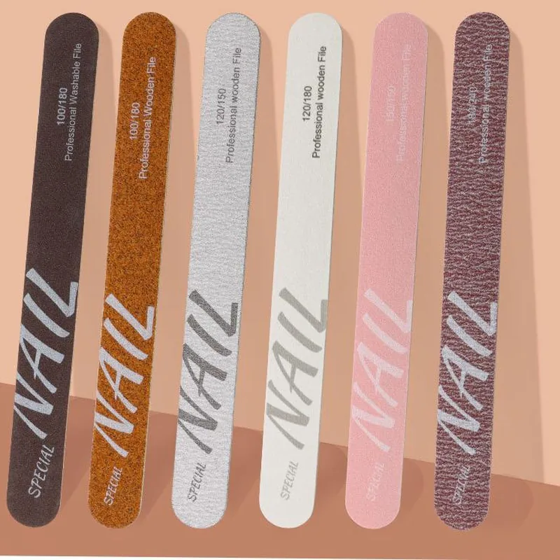 Six wooden nail files in dark brown, orange, silver, white, pink and maroon flat-laid on a peach background