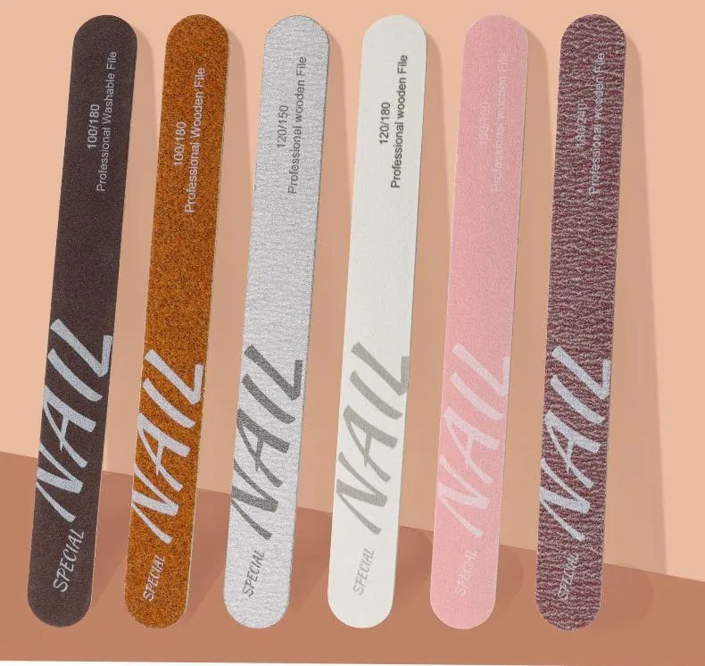 Six wooden nail files in dark brown, orange, silver, white, pink and maroon flat-laid on a peach background