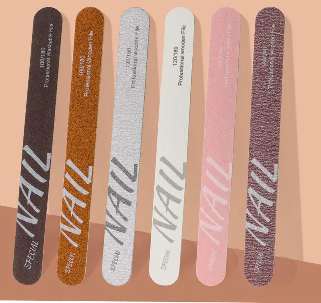 Six wooden nail files in dark brown, orange, silver, white, pink and maroon flat-laid on a peach background