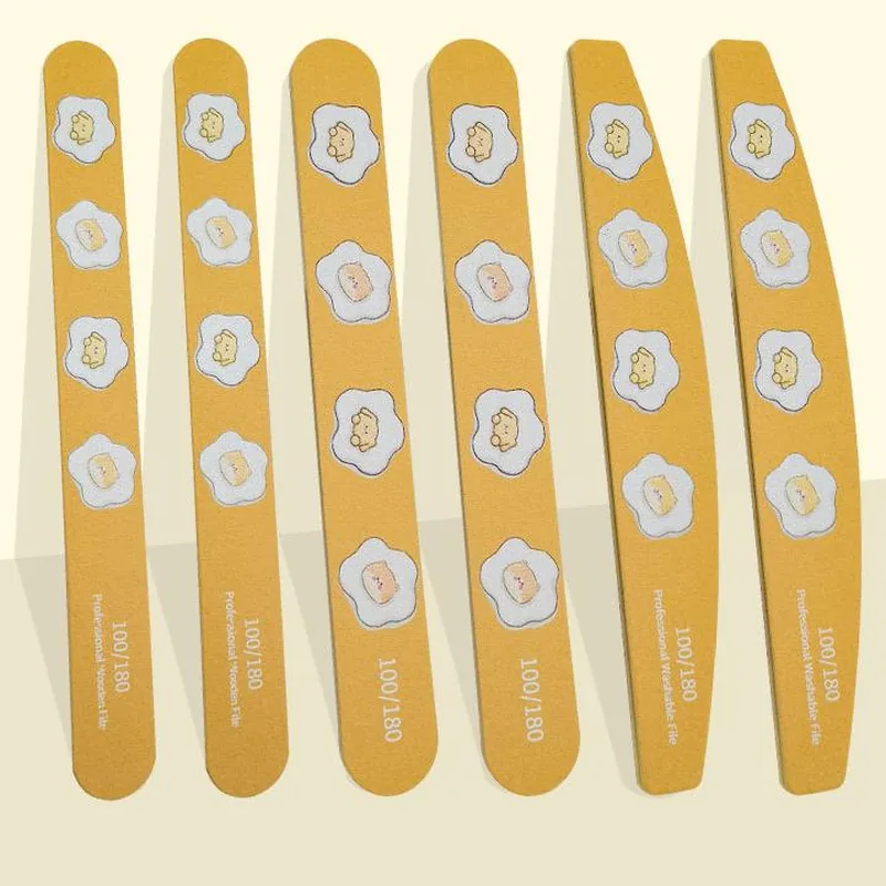 Six yellow egg-flower print wooden nail files flat-laid on a cream background