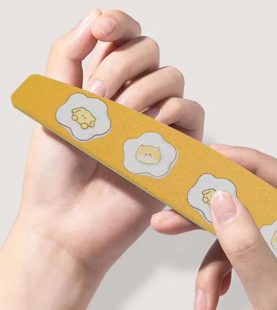 Hand holding the yellow egg-flower print nail file with the printed face toward the camera