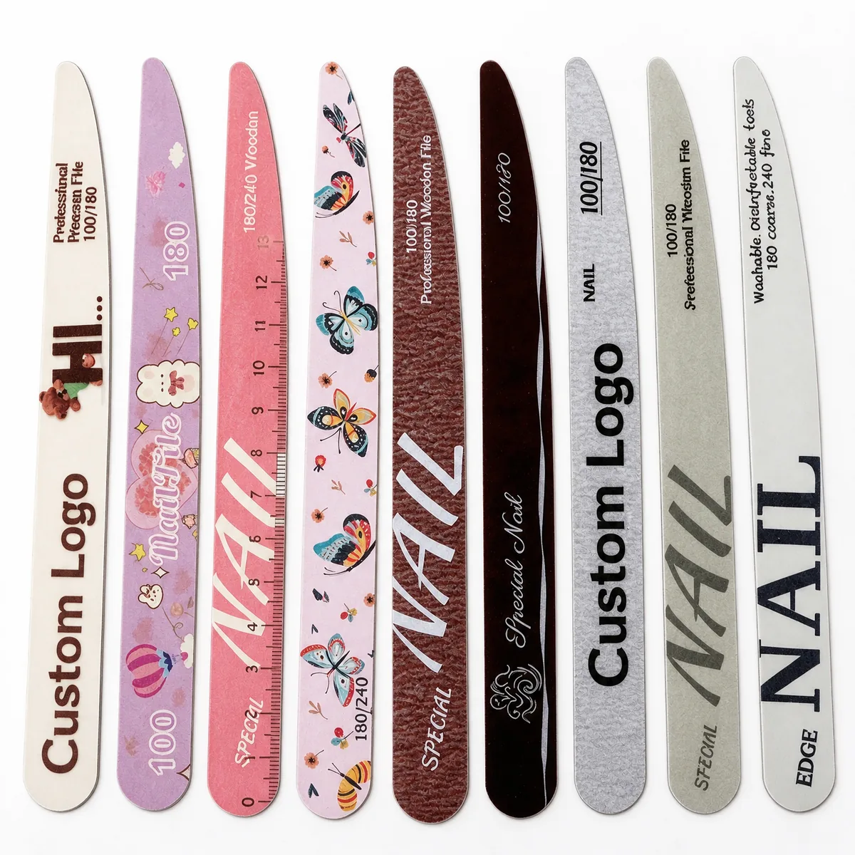 Nine ultra-thin printed wooden nail files in assorted designs lined up on a white background