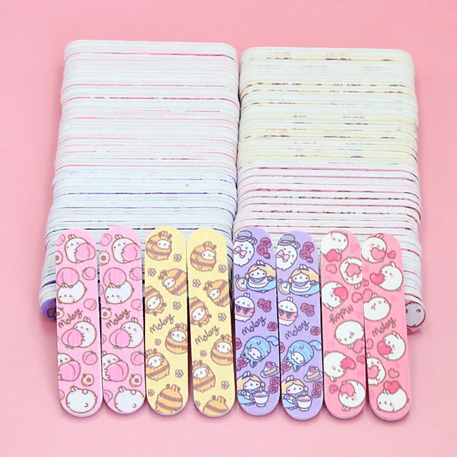 Mini cartoon-print nail files standing in front of two block stacks showing the printed designs